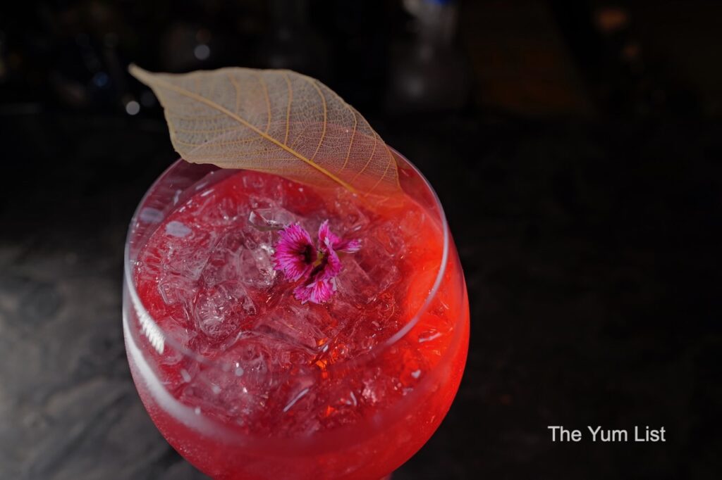 Desire Speakeasy Plaza Batai Pink Panther  - red cocktail in bowl glass with pink flower garnish