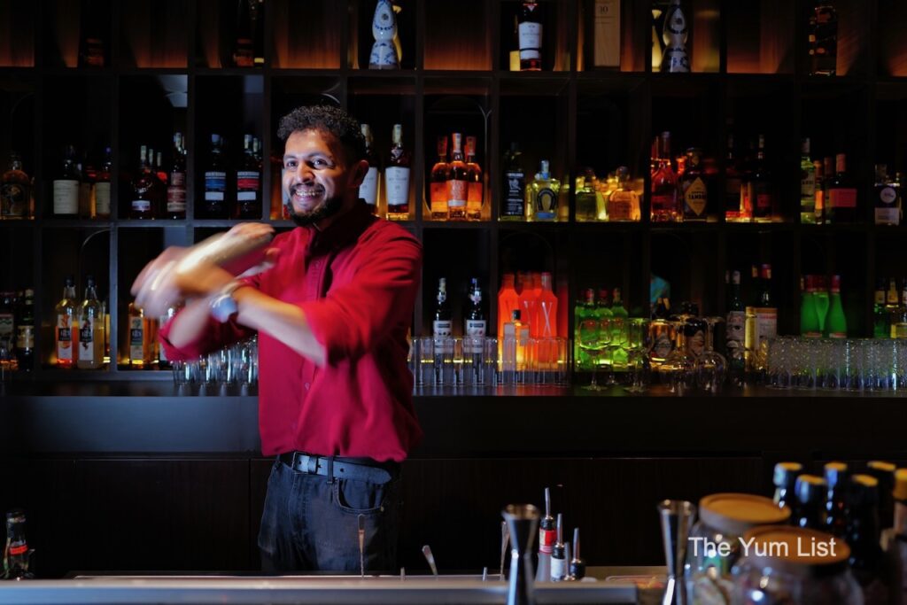 Desire Speakeasy Plaza Batai bartender in red shirt shaking cocktail