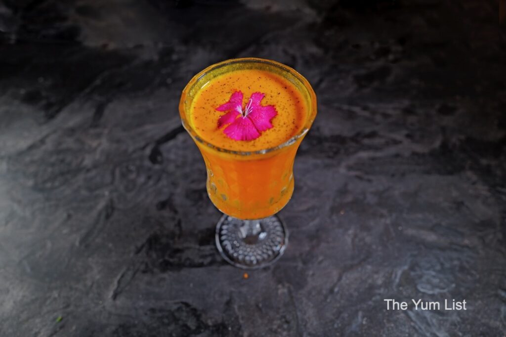 Desire Speakeasy Plaza Batai - Lipa Tea turmeric cocktail with pink flower garnish