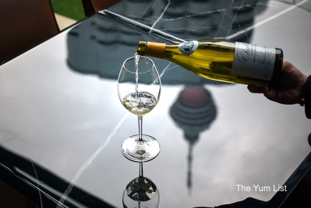 Louis Latour Chablis Premier Cru Montmains pouring into glass with KL tower reflected on table